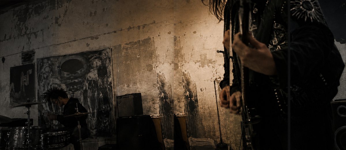 Band performing inside a raw studio with artwork and equipment surrounding the musicians.